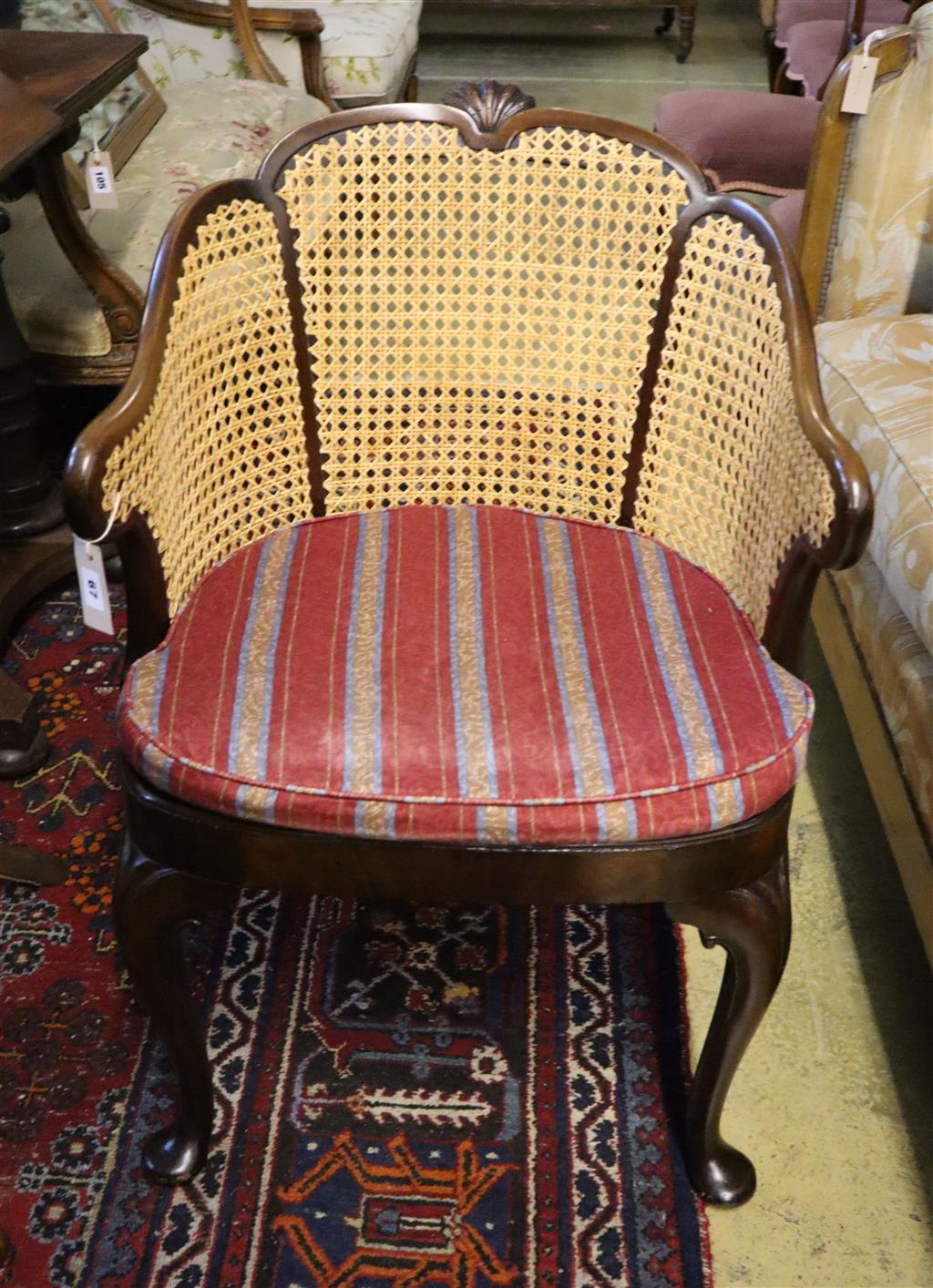 A 1920s Georgian style mahogany bergere with caned sides and cabriole legs